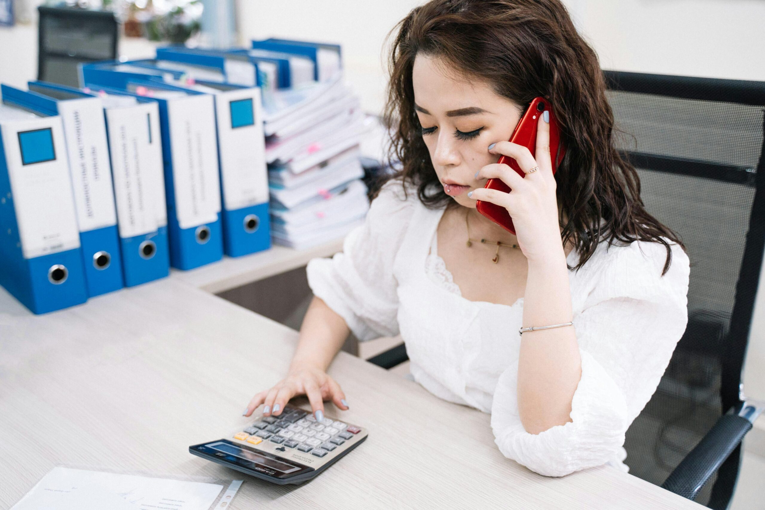Woman talking on the phone while using calculator